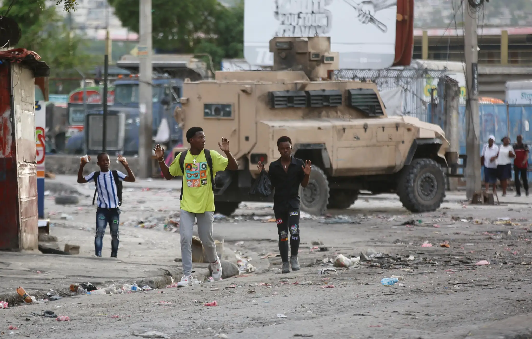 Mladíci dvíhajú ruky, aby ukázali polícii, že nemajú pri sebe zbrane počas operácie proti gangom v haitskej metropole Port-au-Prince