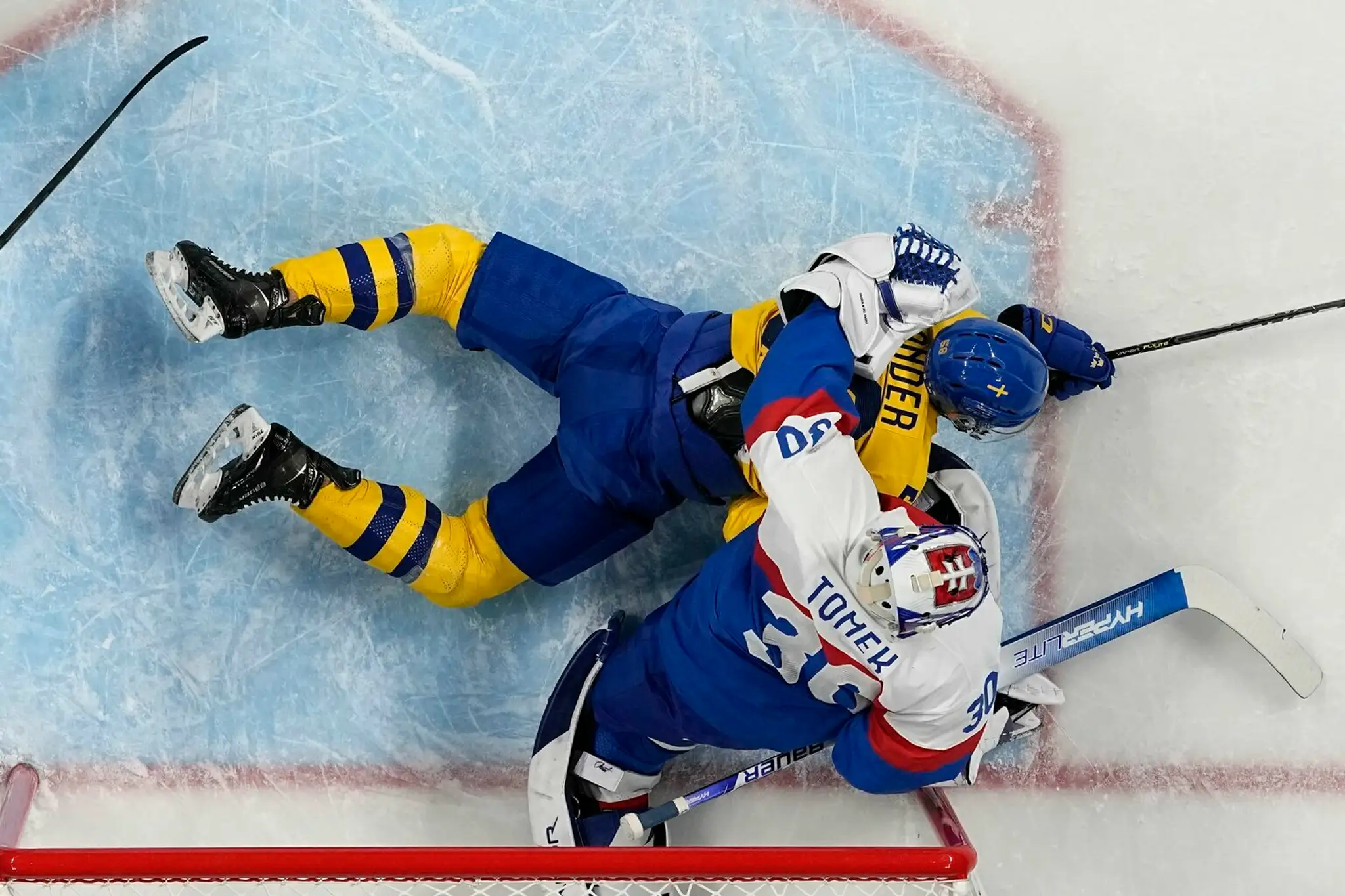 Švéd Anton Lander a slovenký gólman Matej Tomek v zápase ZOH 2022.