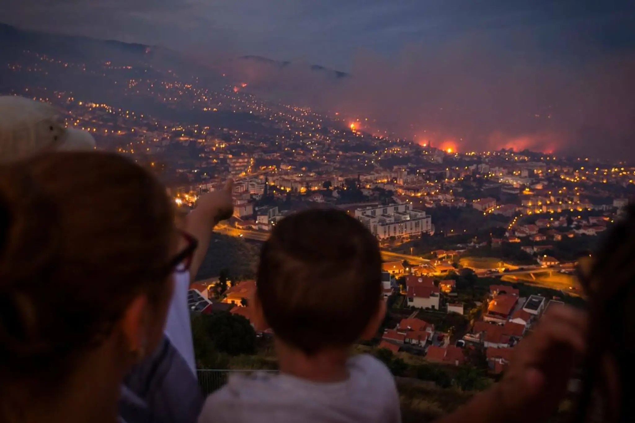 Evakuovaní obyvatelia sledujú skazu.