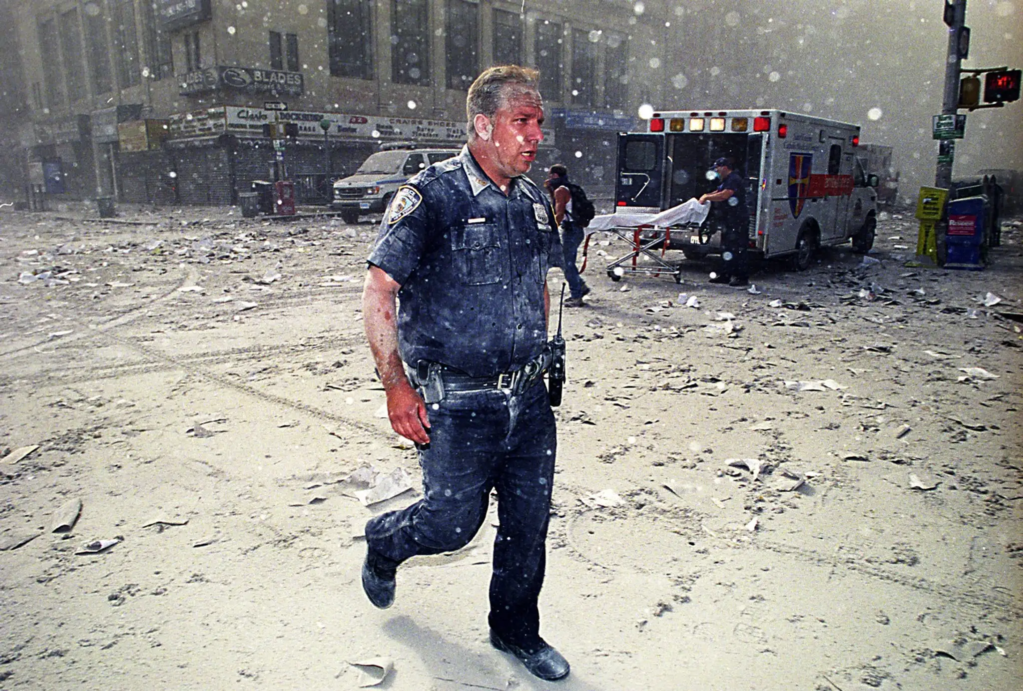 Policajt v uliciach dolného Manhattanu po útokoch na Svetové obchodné centrum. Tisíce ľudí zasiahli trosky, sklo či hustý prach.