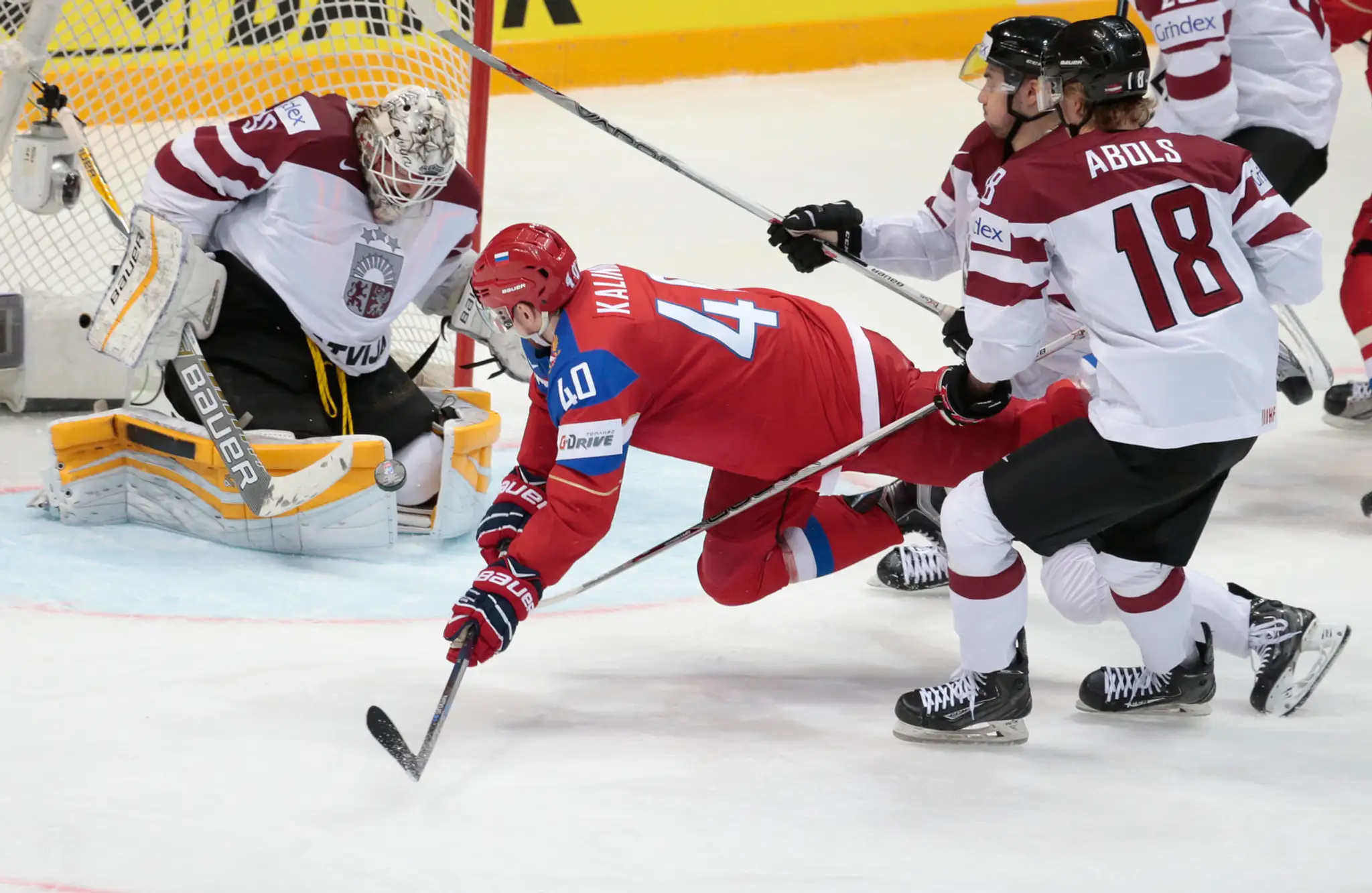 Na snímke Rus Sergej Kalinin (v červenom) a Lotyš Elvis Merzlikins (v bránke)