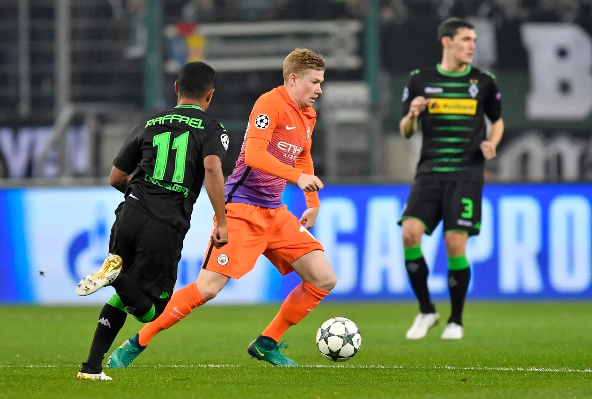 Motor zálohy Manchestru City Kevin de Bruyne (v oranžovom) stíhaný Raffaelom z Borussie Mönchengladbach v dueli LM.