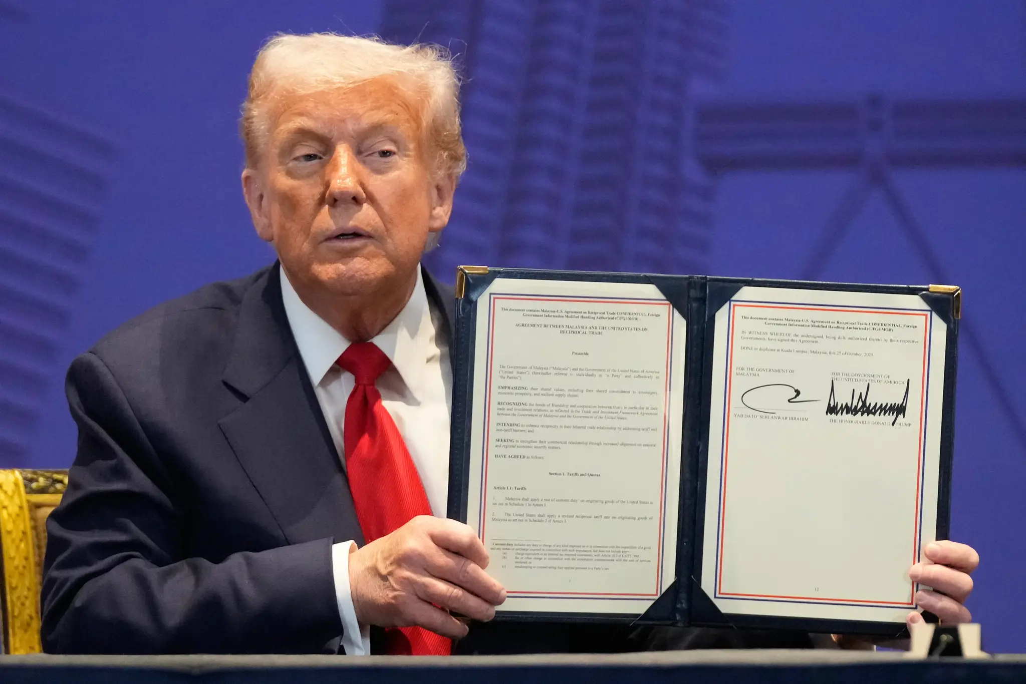 Donald Trump drží v ruke podpísanú dohodu medzi Kambodžou a Thajskom.