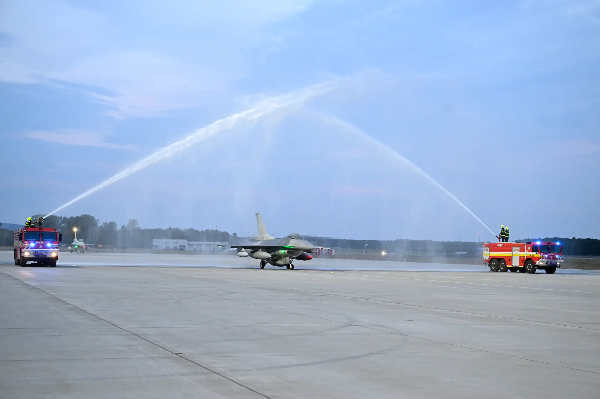 Stíhačky F-16 symbolicky prechádzajú tzv. slávobránou z hasičských striekačiek v priestoroch Leteckej základne Malacky-Kuchyňa.
