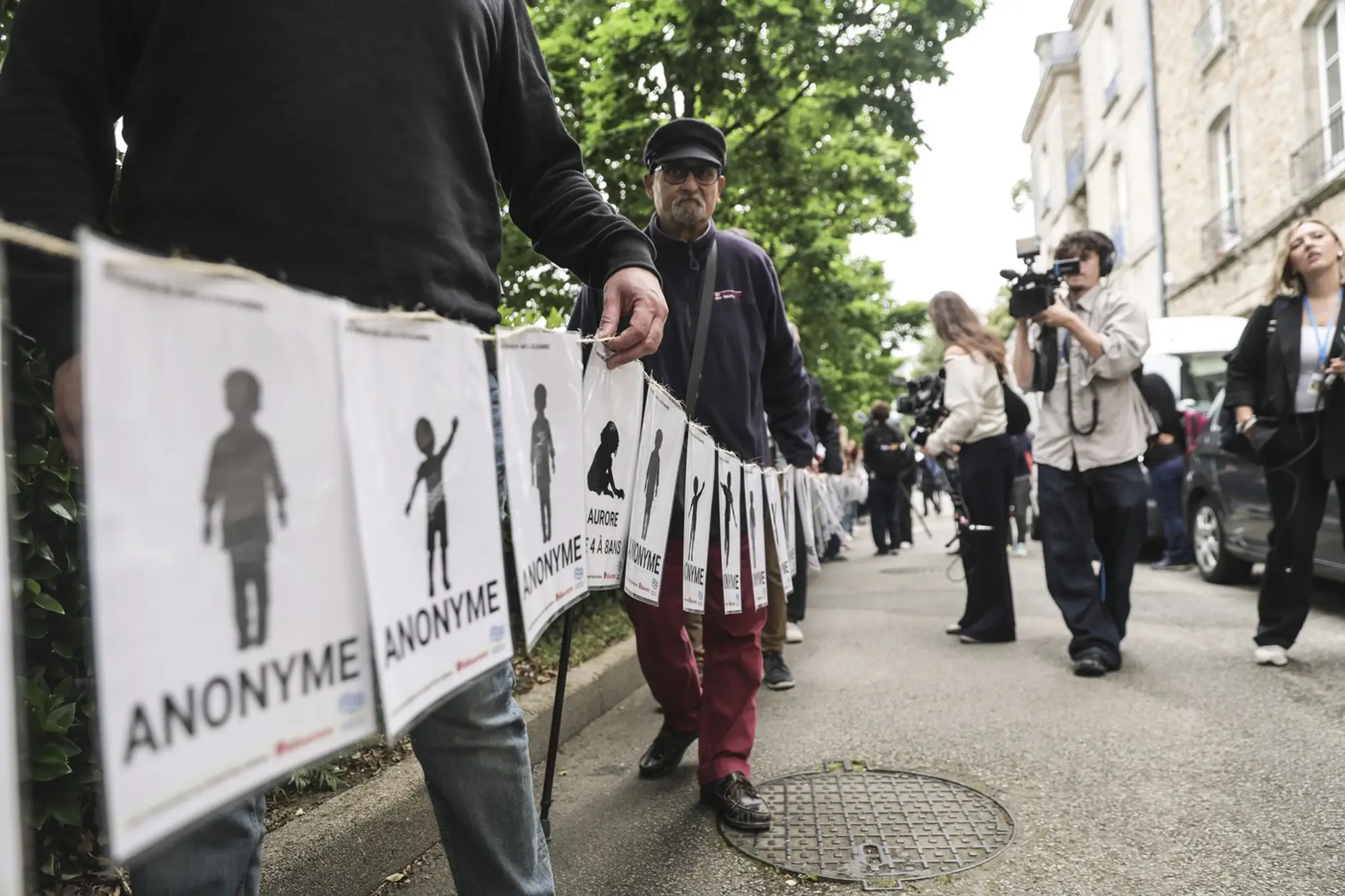 Ľudia vrátane obetí nesú transparenty predstavujúce obete Joela Le Scouarneca v deň vynesenia rozsudku v procese s francúzskym chirurgom vo Vannes.