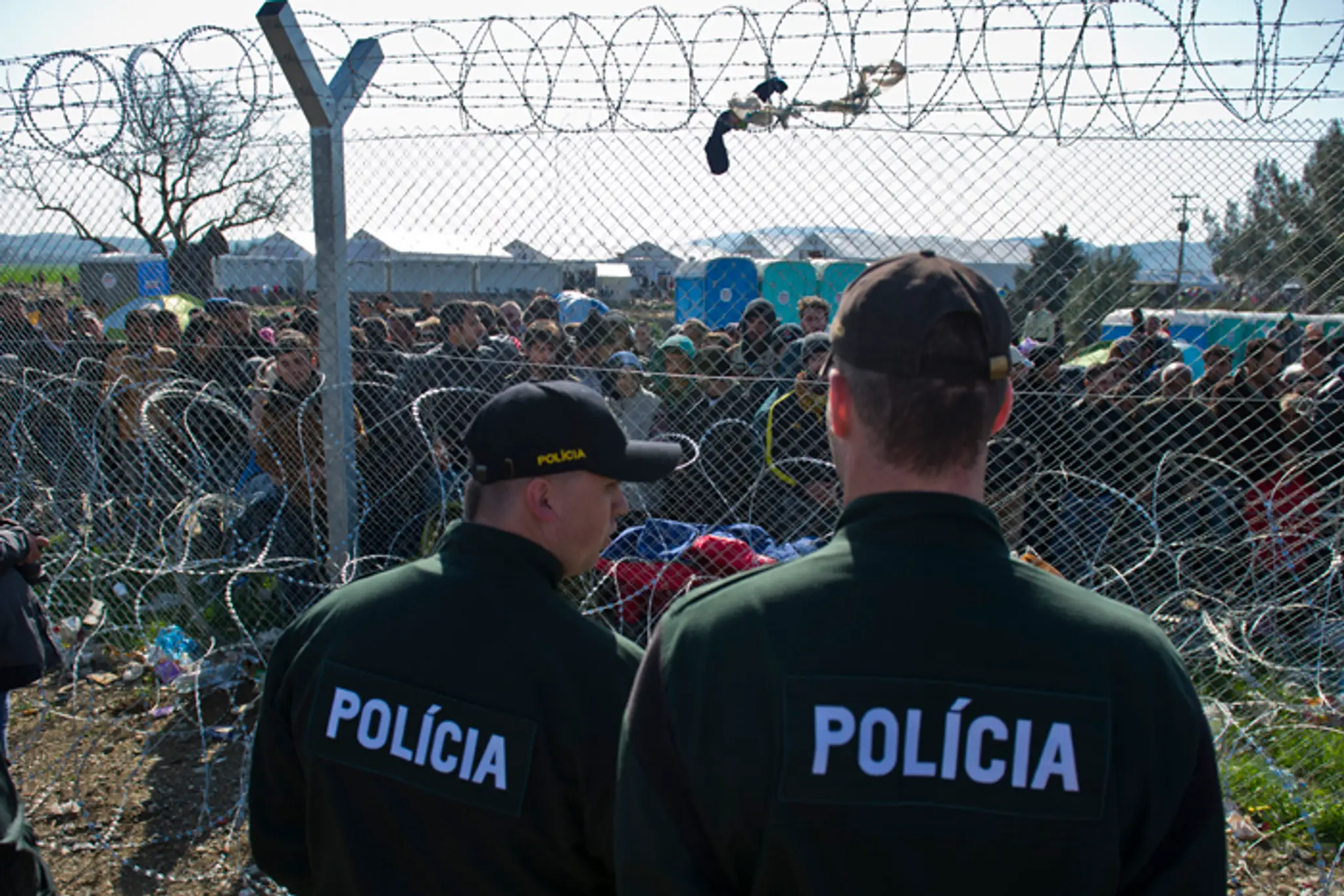 Na snímke migranti na gréckej strane hranice a slovenskí policajti.