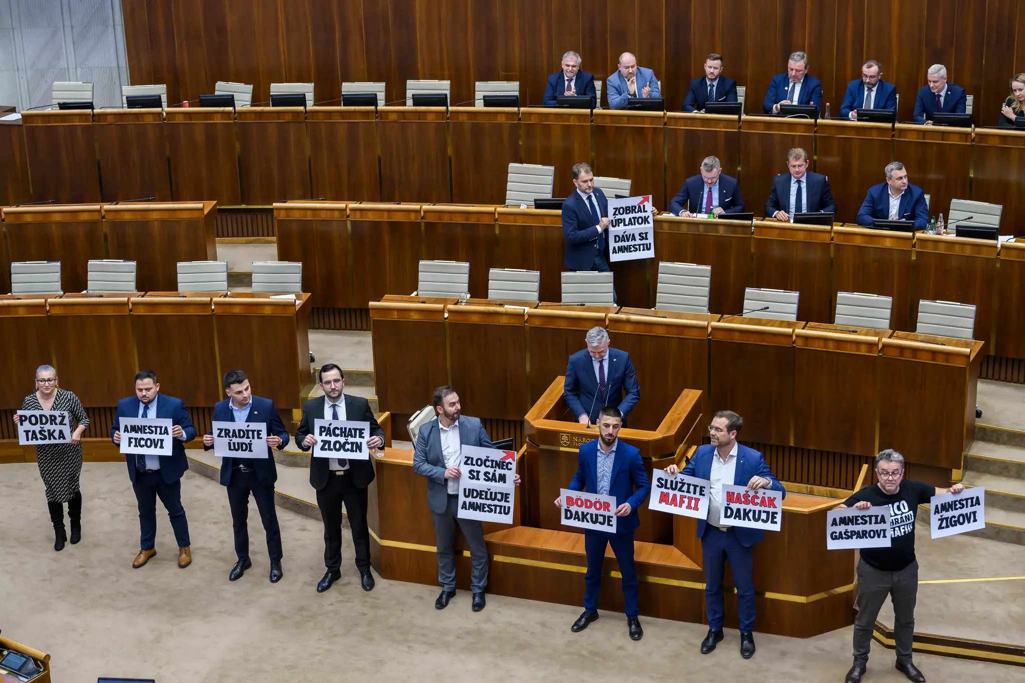 Opoziční poslanci s transparentami počas hlasovania o novele Trestného zákona.