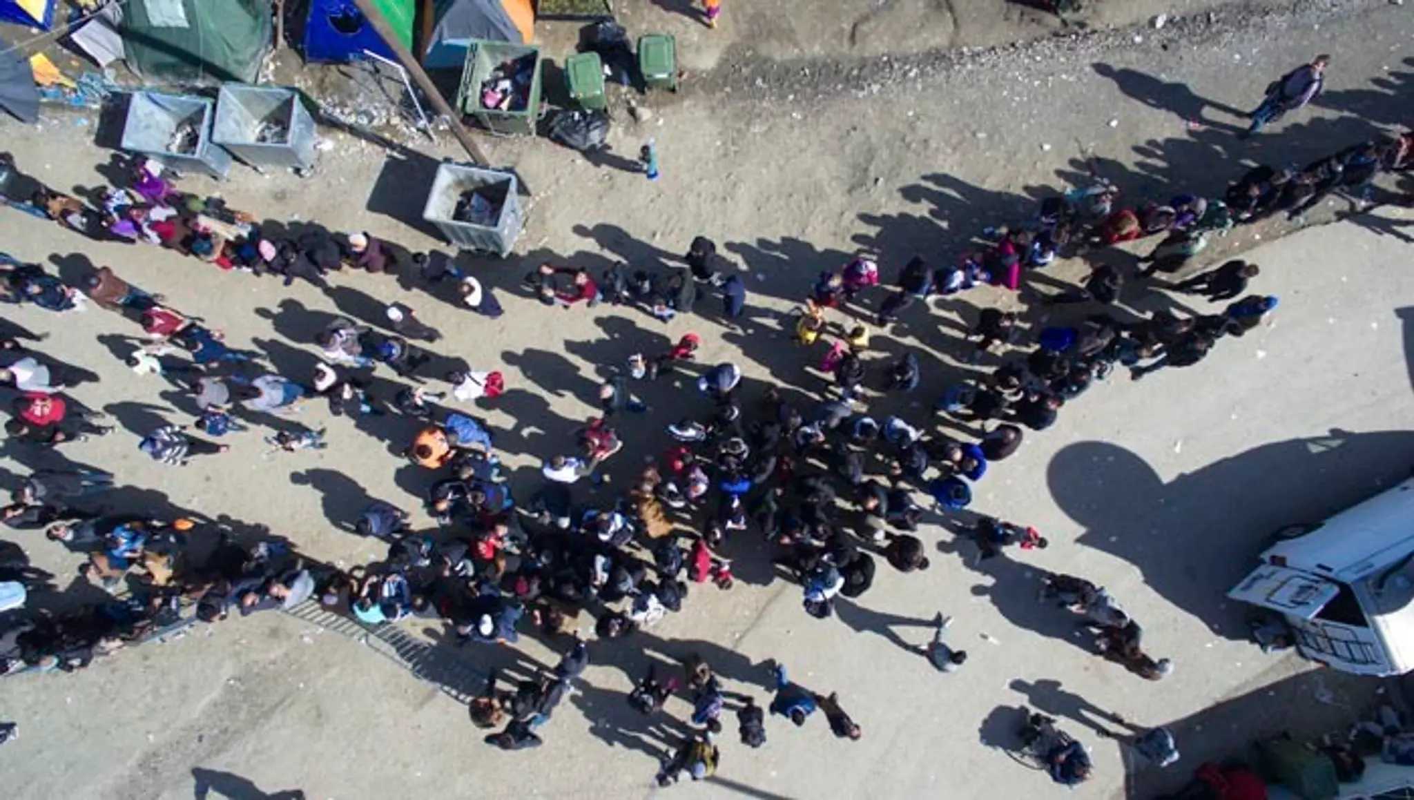 Migranti čakajú v rade na jedlo distribuované mimovládnymi organizáciami v utečeneckom tábore pri severogréckej dedine Idomeni n