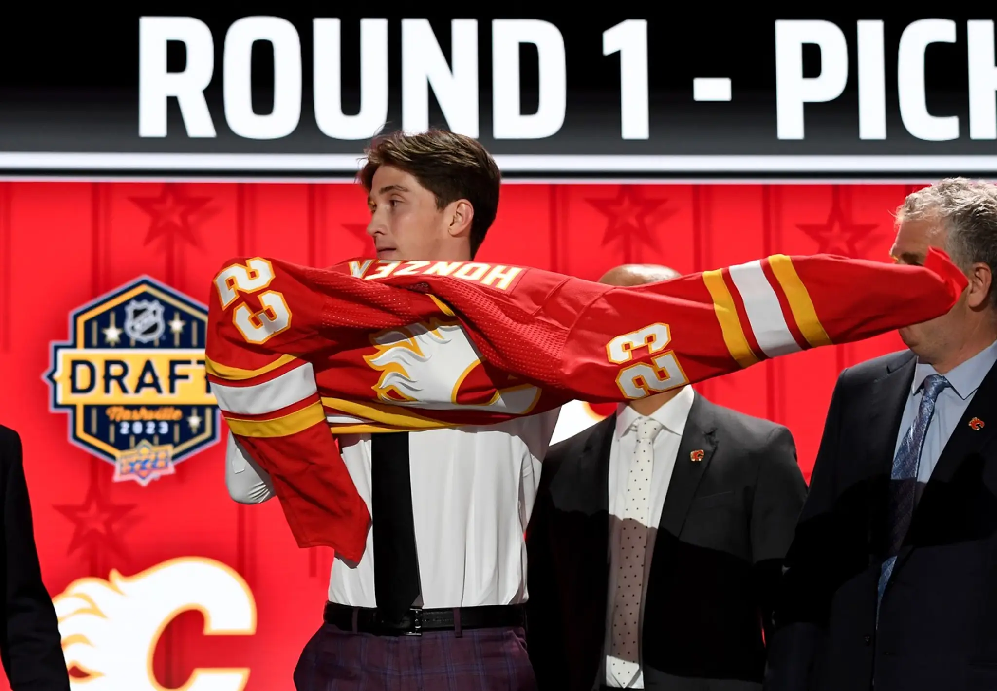 Samuel Honzek si oblieka dres Calgary na NHL drafte 2023.