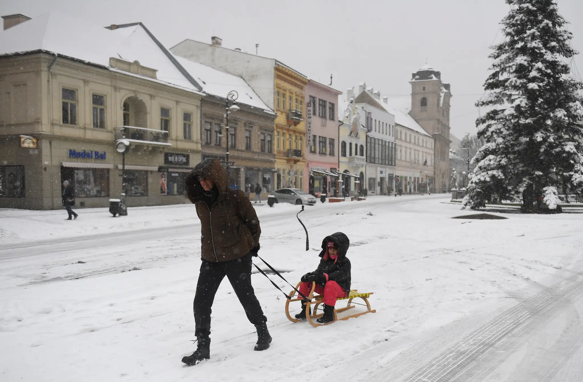 Na snímke žena vezie dieťa na saniach počas sneženia v centre Košíc.