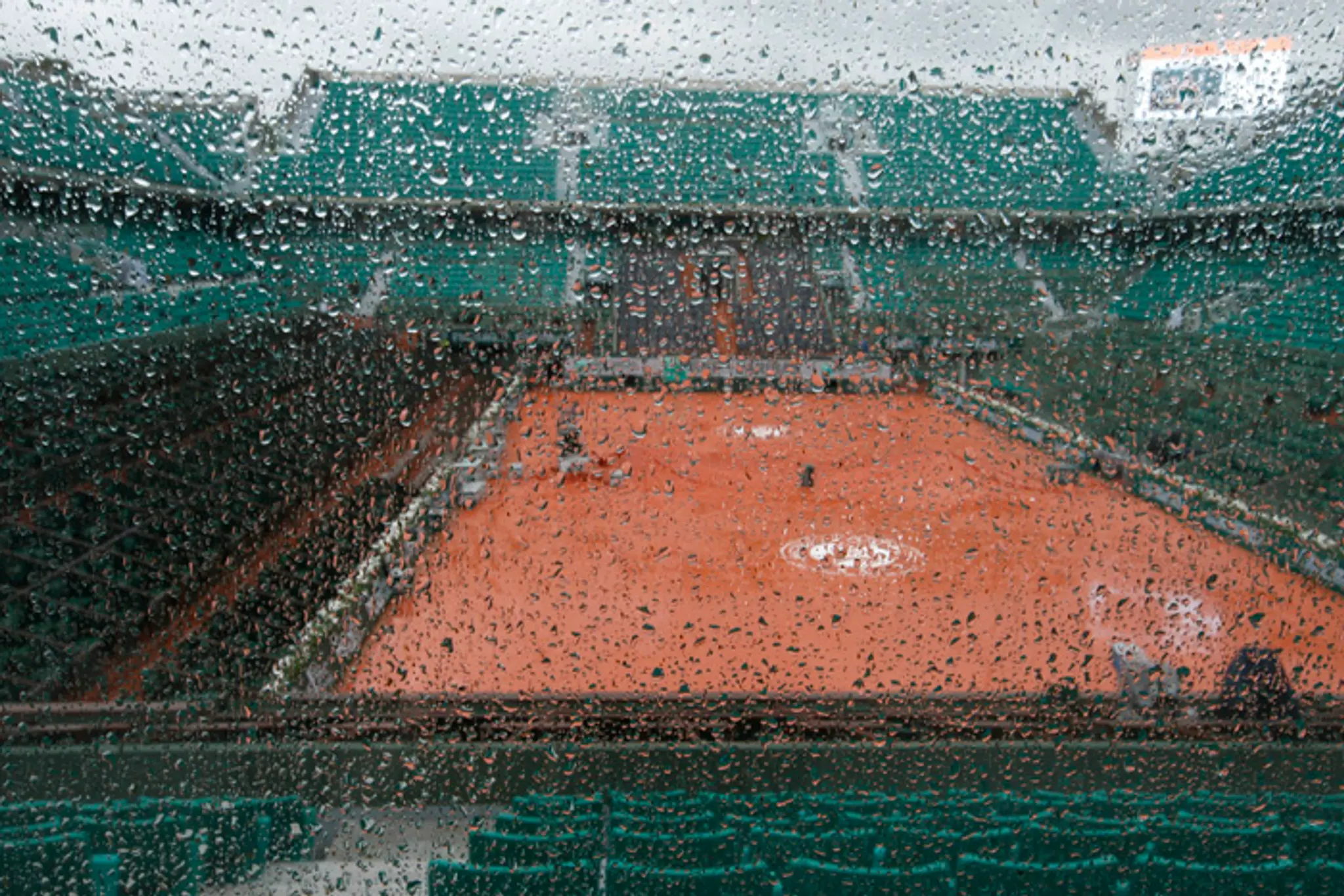 Centrálny kurt vidieť cez sklo počas dažďa pred začiatkom zápasov 1. kola na grandslamovom turnaji Roland Garros.