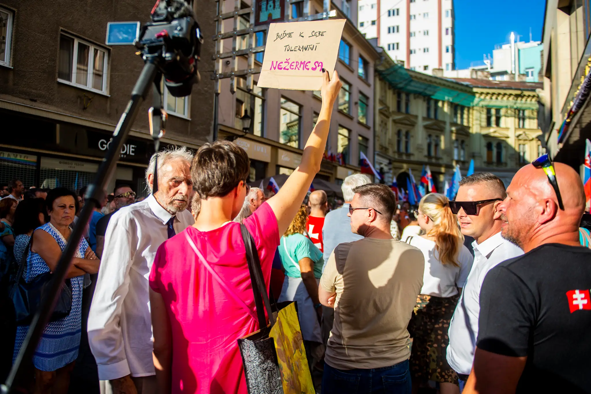 Žena s transparentom pri účastníkoch protestu proti aktuálnej reklamnej kampani bratislavského Divadla Pavla Országha Hviezdoslava.