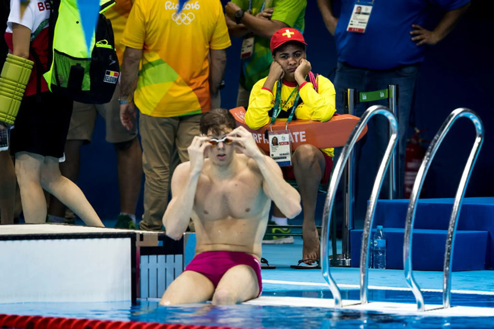 Unudená plavčíčka sedí a pozerá na olympijský bazén.