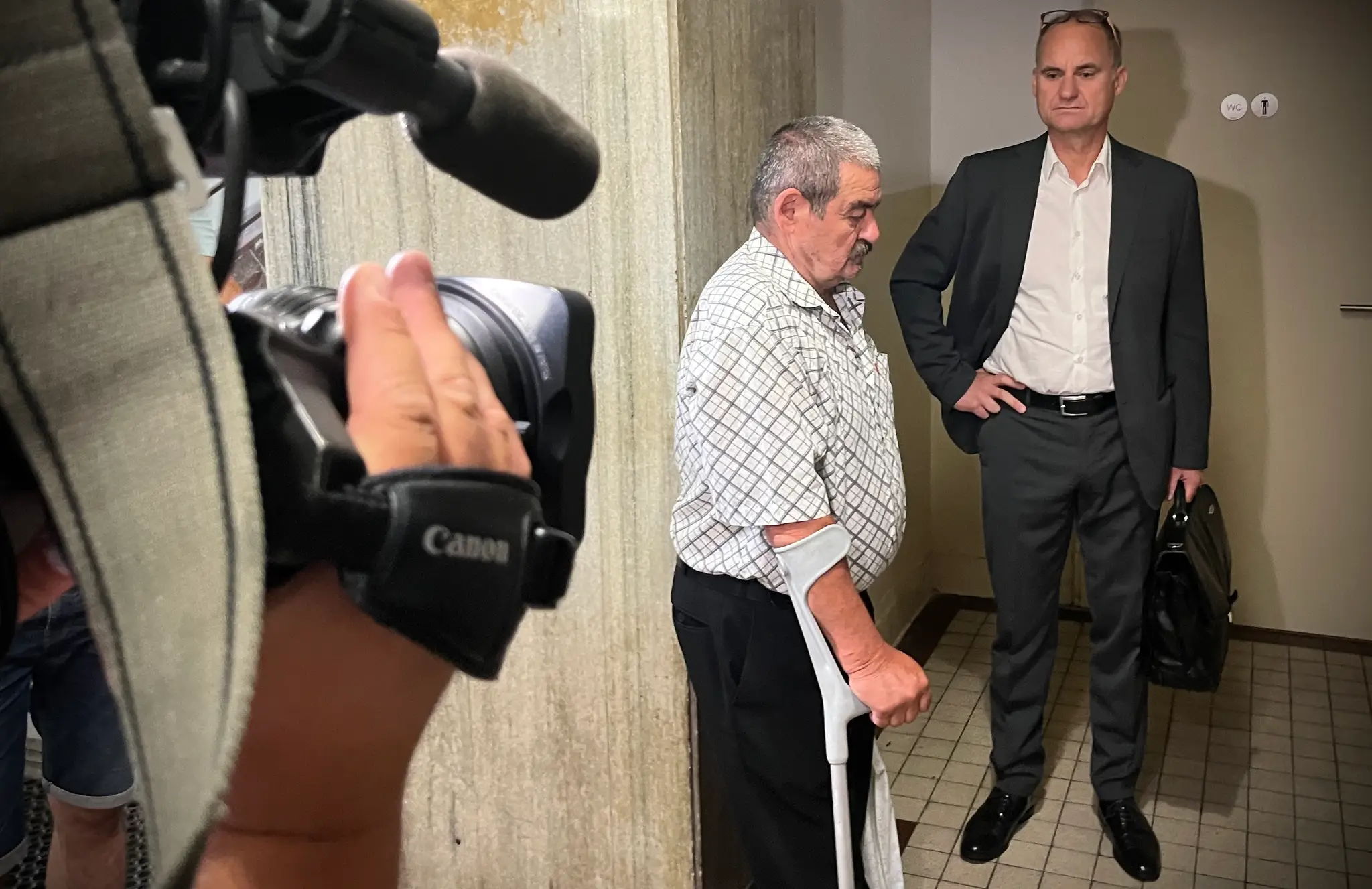 Dôchodca stojí v budove súdu.
