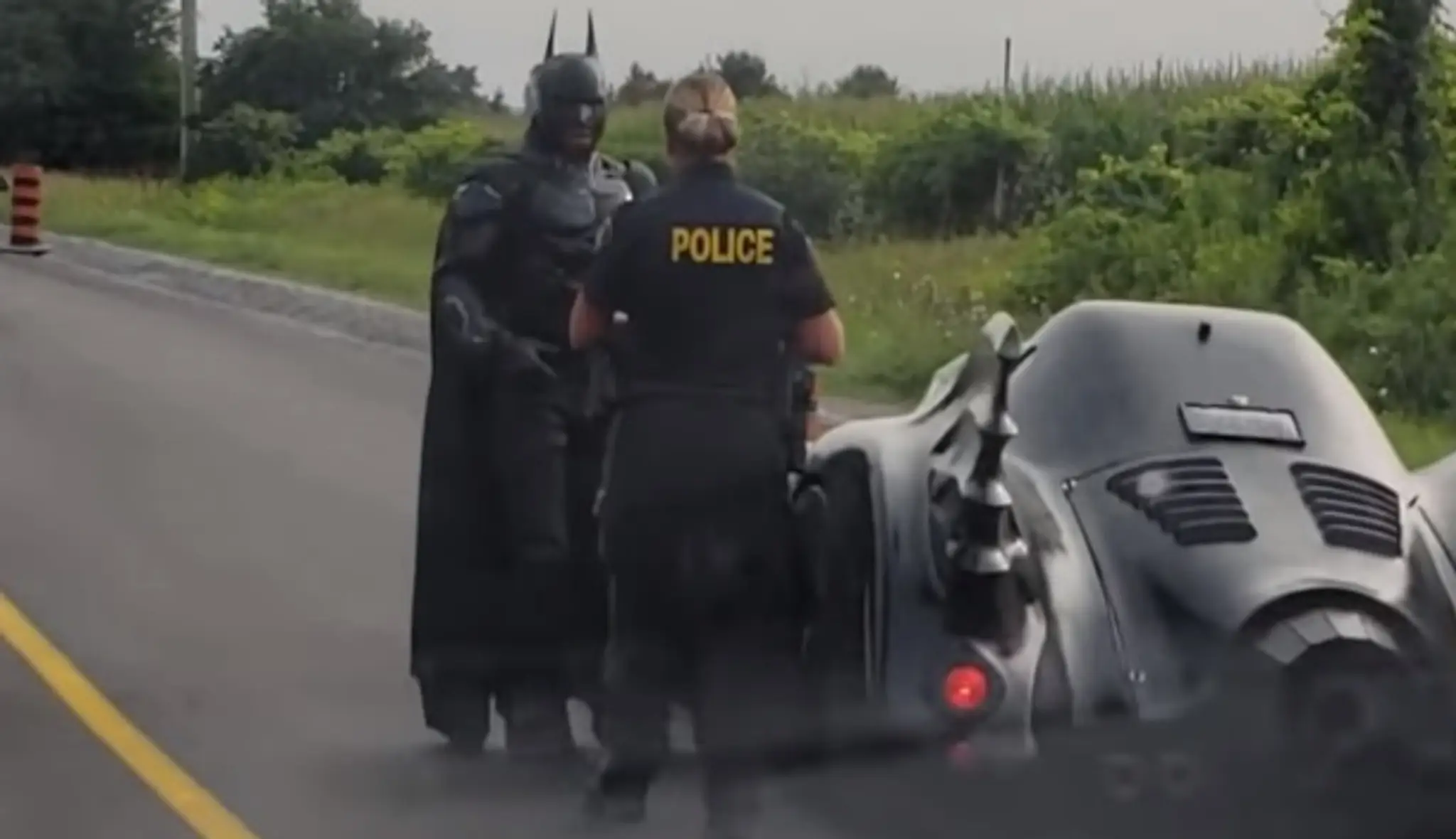 Policajtka kontroluje muža prezlečeného za Batmana.