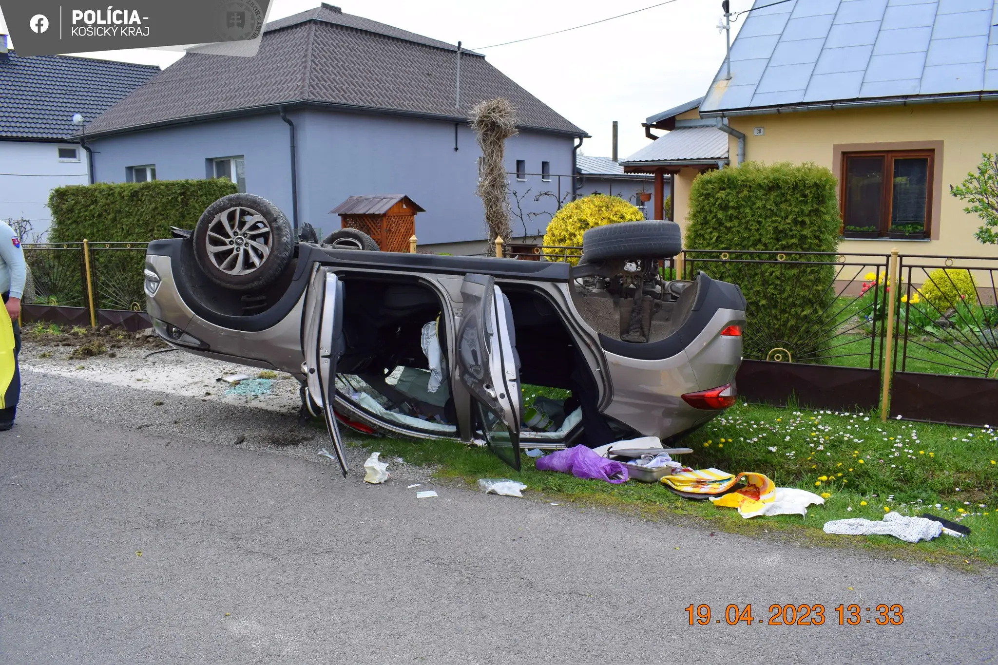 Na snímke je zachytená dopravná nehoda, pri ktorej skončilo auto na streche. V pozadí sú rodinné domy a okolo auta rozhádzané veci, ktoré z neho vypadli.