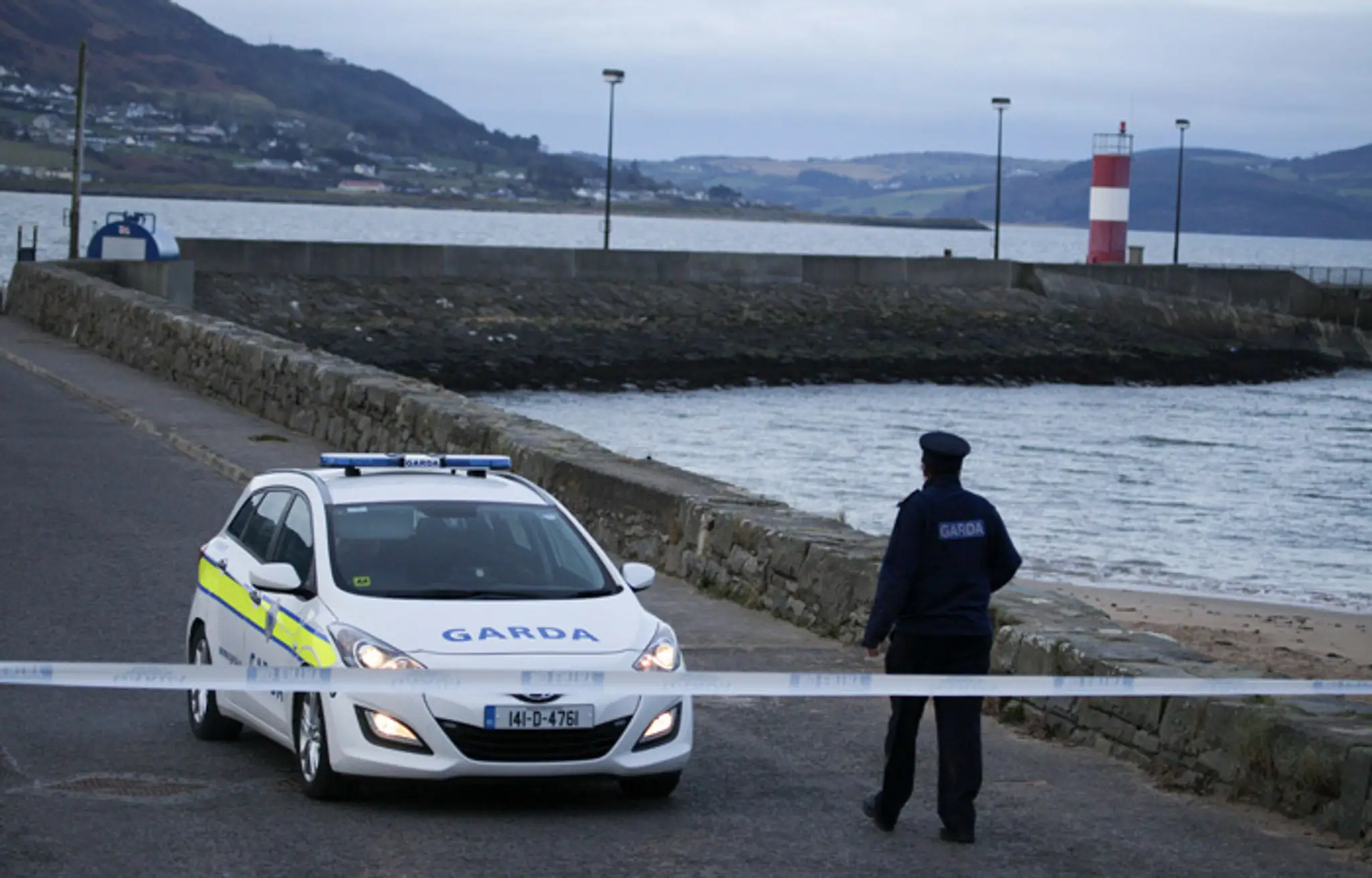 Írsky policajt hliadkuje v Buncrana Pier, kde spadlo do mora auto s piatimi ľuďmi.