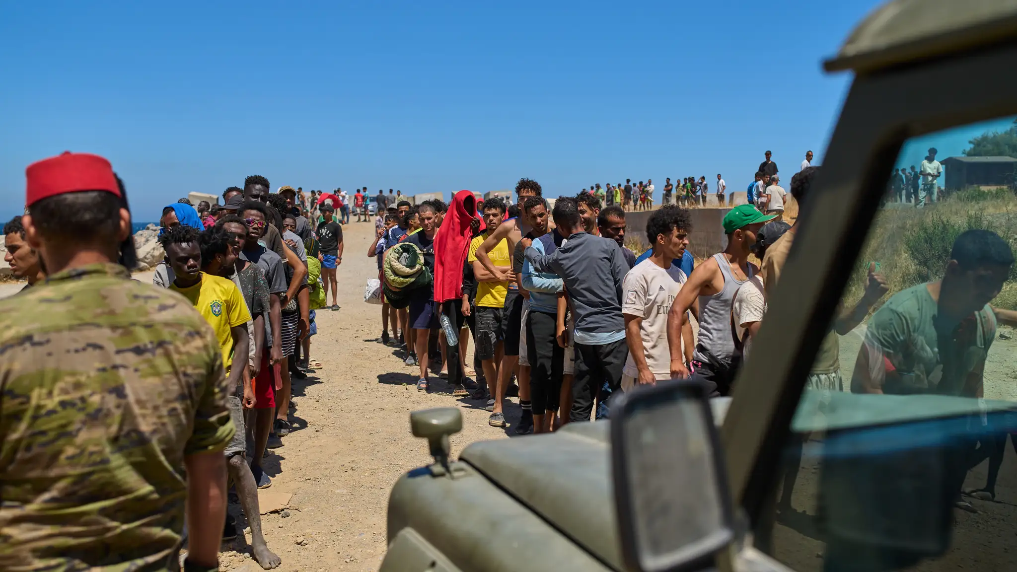 Migranti, ktorí prekročili hranice do Španielska z Maroka, čakajú v rade na vodu, ktorú rozdávajú španielski vojaci.