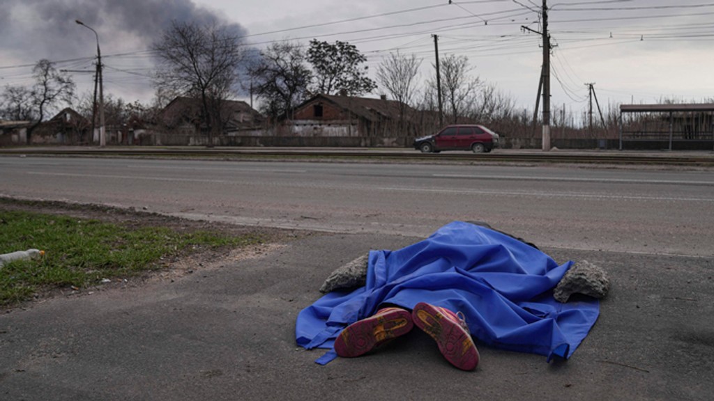 Mŕtve telo prikryté plachtou leží na ceste v Mariupole.