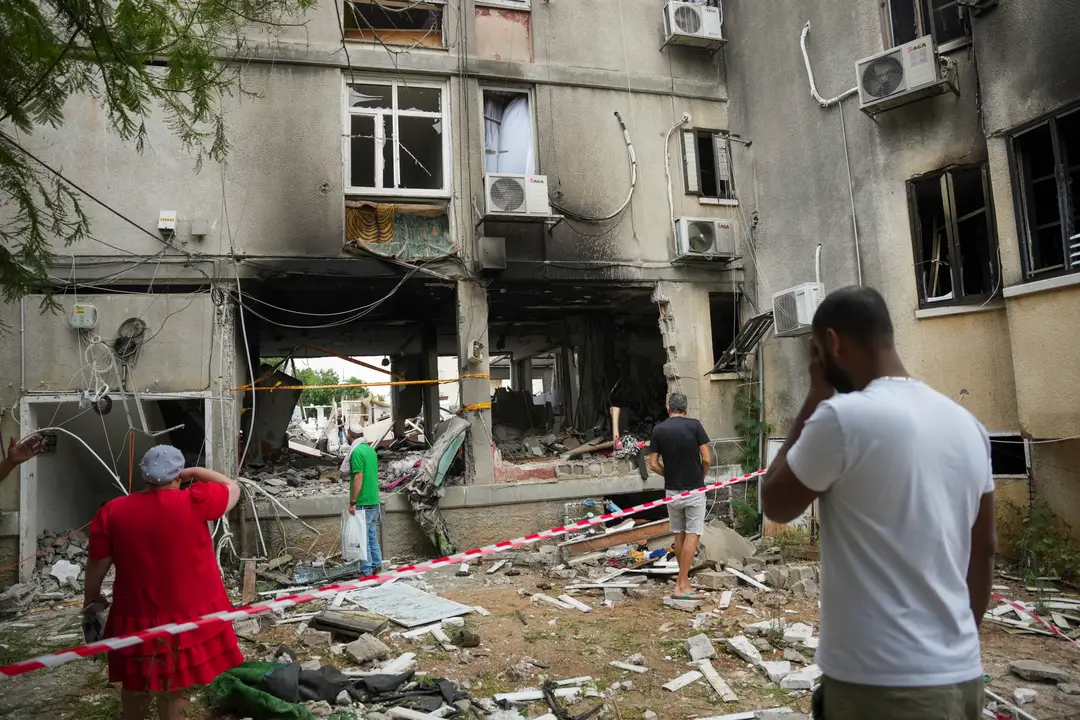 Izraelčania kontrolujú poškodenú obytnú budovu po zásahu raketou vypálenou z pásma Gazy v meste Aškelon.