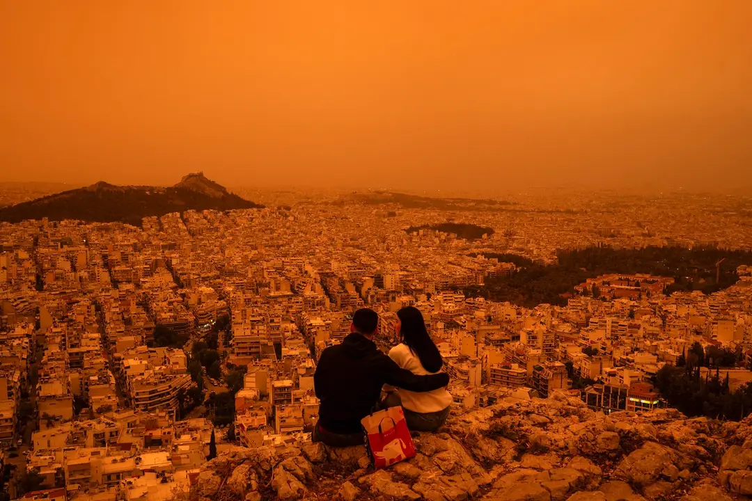 Turisti sa pozerajú na Atény zahalené do oranžovej farby saharského prachu.