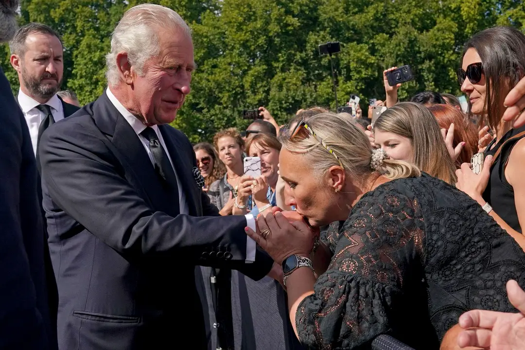 Žena bozkáva ruku britskému kráľovi Karolovi III.