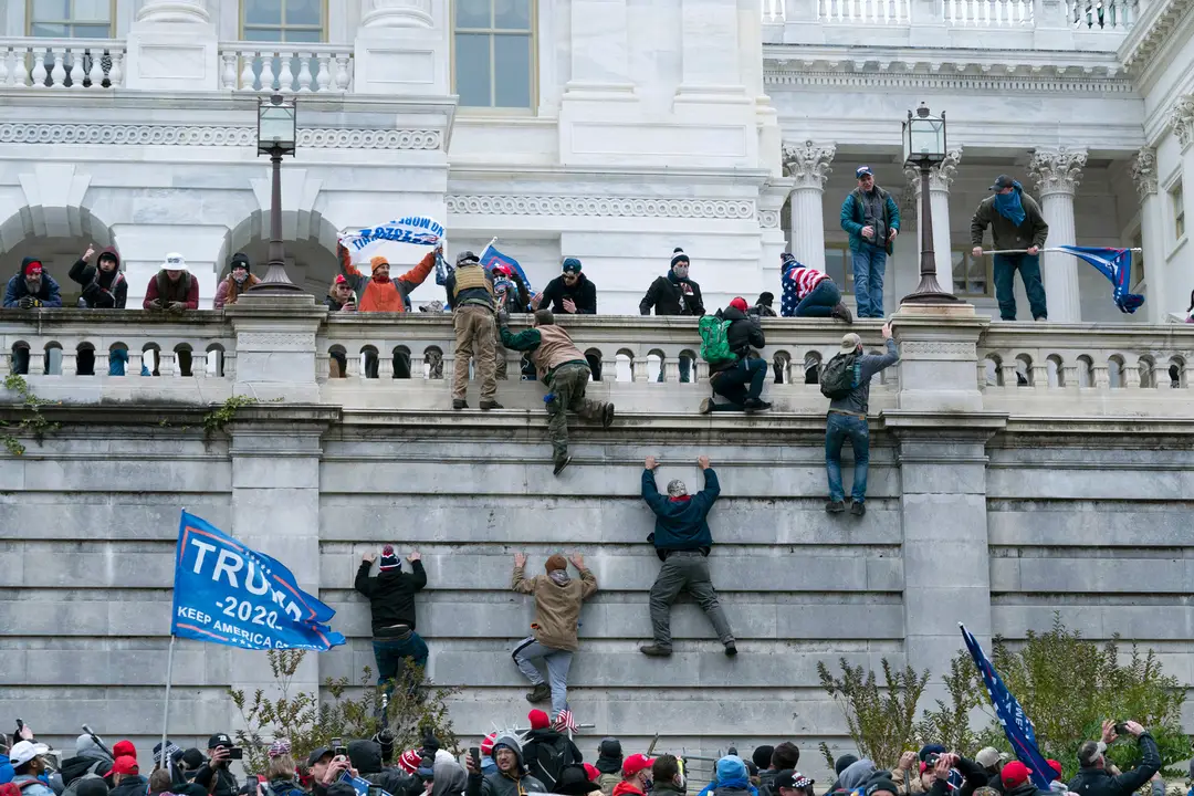 Na snímke stúpenci amerického prezidenta Donalda Trumpa sa vešajú na budovu Kapitolu vo Washingtone.