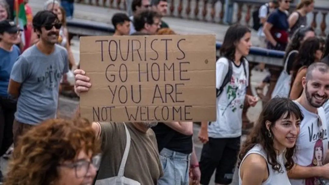 Transparent s nápisom „turisti, choďte domov, nie ste tu vítaní“ počas protestu v Barcelone. 