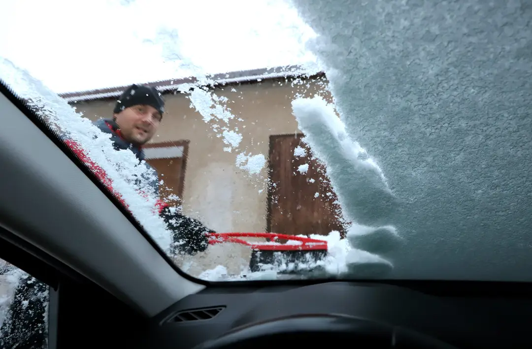 Na snímke vodič odhrabáva sneh z osobného auta počas ranného sneženia vo Zvolene.