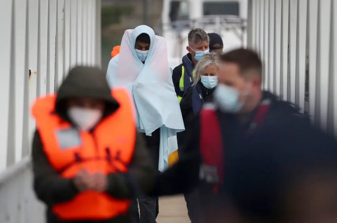 Skupina migrantov je eskortovaná policajtmi do prístavu v anglickom meste Dover.