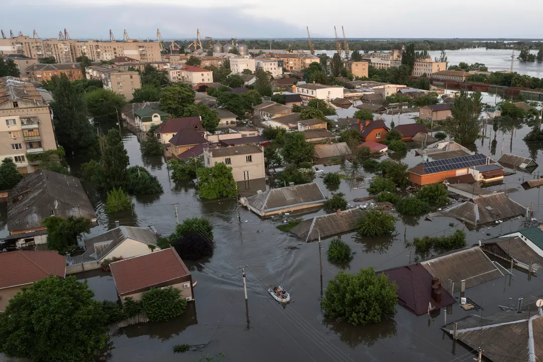 Ľudia jazdia na gumených člnoch v zaplavenej štvrti Chersonu na Ukrajine.