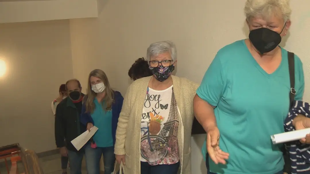 Ľudia čakajú na očkovanie v rade na schodoch.