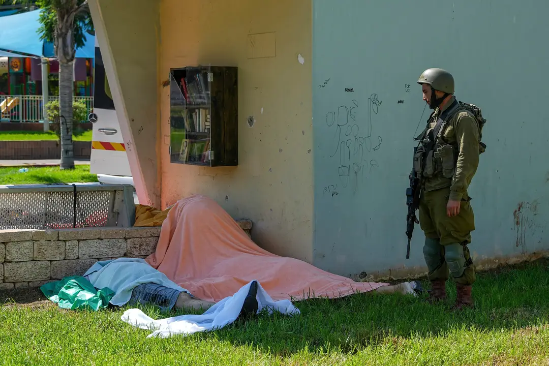 Izraelský vojak stojí pri telách Izraelčanov zabitých palestínskymi ozbrojenými militantmi.
