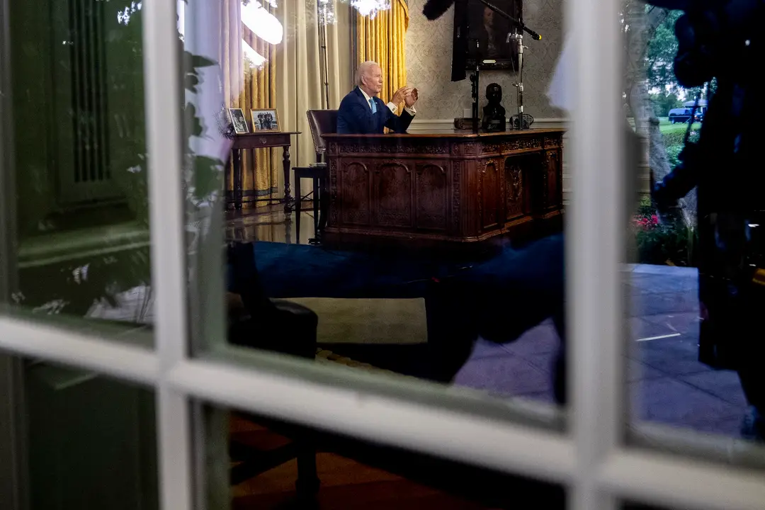 Joe Biden sedi za stolom vo svojej pracovnice v Bielom dome.