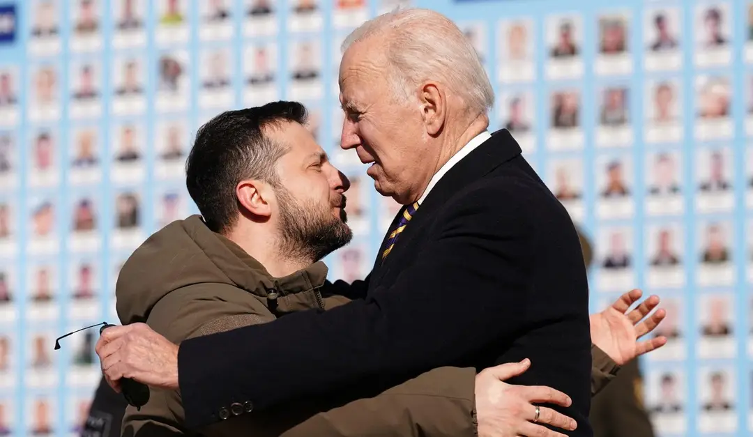 Volodymyr Zelenskyj a Joe Biden v objatí pred pamätníkom obetiam vojny na Ukrajine.