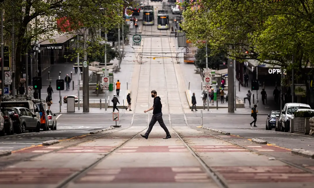 Na archívnej snímke z 30. septembra 2021 ľudia kráčajú cez cestu v Melbourne.