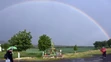 Ľudia v daždi prechádzajú pred dúhov v obci Čerhov.