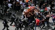 Izraelskí vojaci a policajti zasahujú proti nahnevanému davu na pohrebe novinára televízie Al Jazeera.
