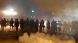 Príslušníci polície kráčajú v hustom dyme pošas rasovo motivovanej demonštrácie v americkom meste Ferguson.