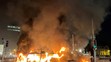 Na snímke auto a autobus horia  počas demonštrácie po útoku v centre Dublinu