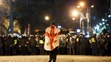 Demonštrant s gruzínskou vlajkou kráča k policajtom počas protestu pred budovou parlamentu v Tbilisi.