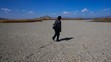Muž kráča po vysušenej časti Titicaca.