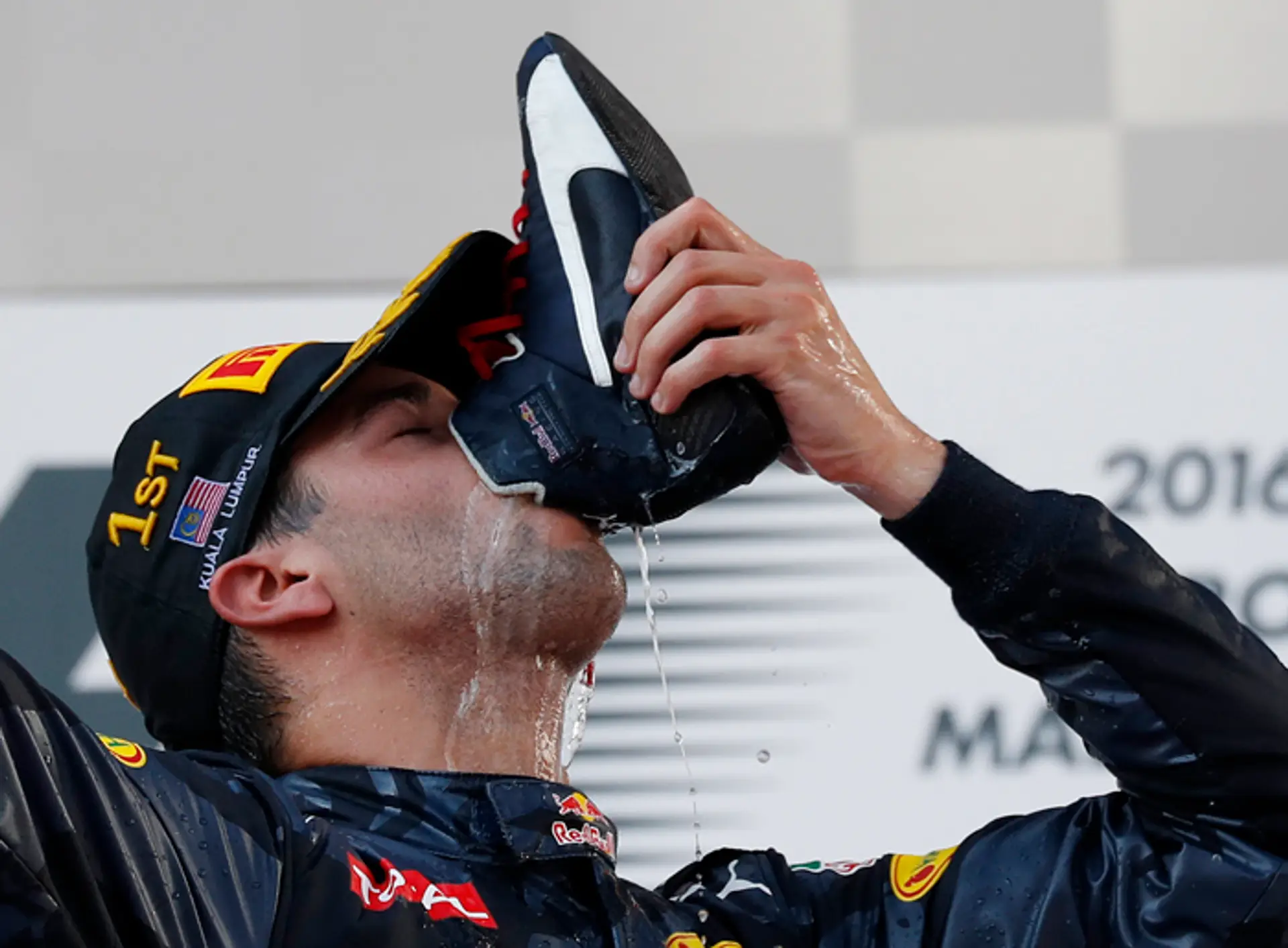 Daniel Ricciardo pije šampanské z topánky počas oslavy víťazstva vo VC Malajzie.