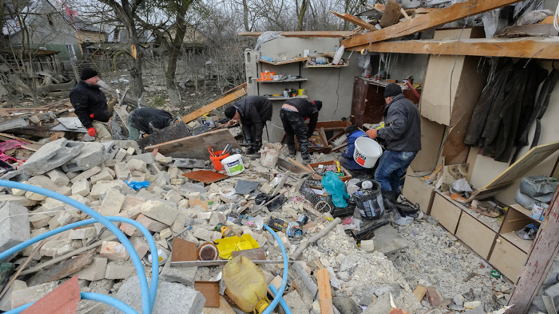 Ľudia odstraňujú materiálne škody na rodinných domoch po raketovom útoku v dedine v Ľvovskej oblasti.