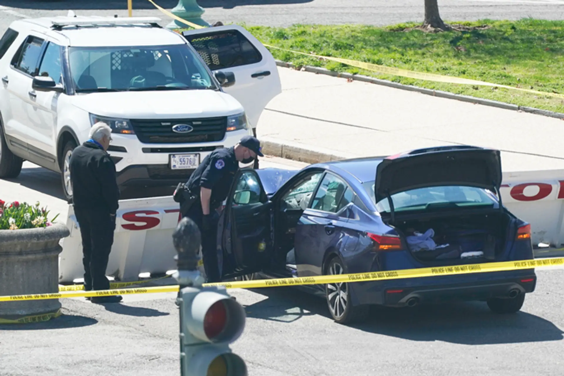 Policajti stoja neďaleko automobilu, ktorý narazil do bariéry pred sídlom vlády USA.