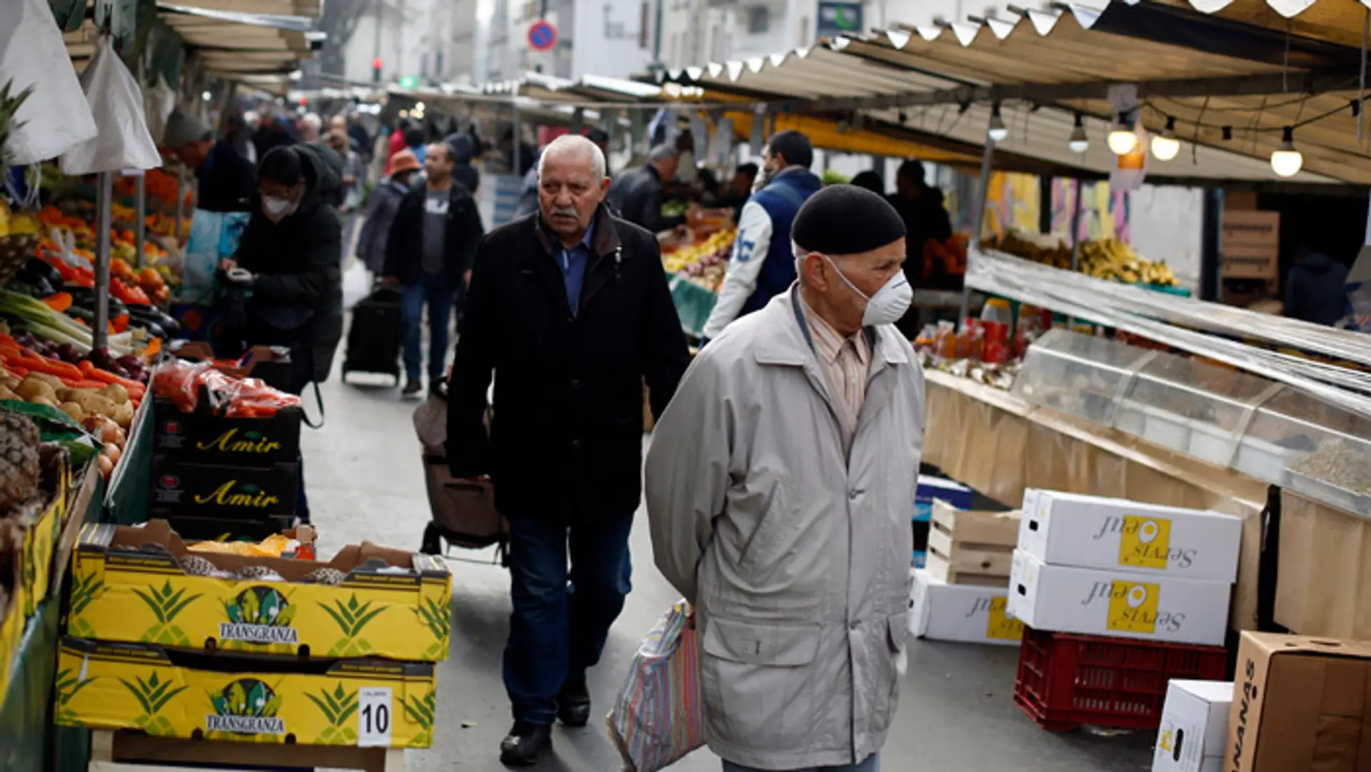 Muž s ochrannou maskou na tvári na trhu v Paríži.