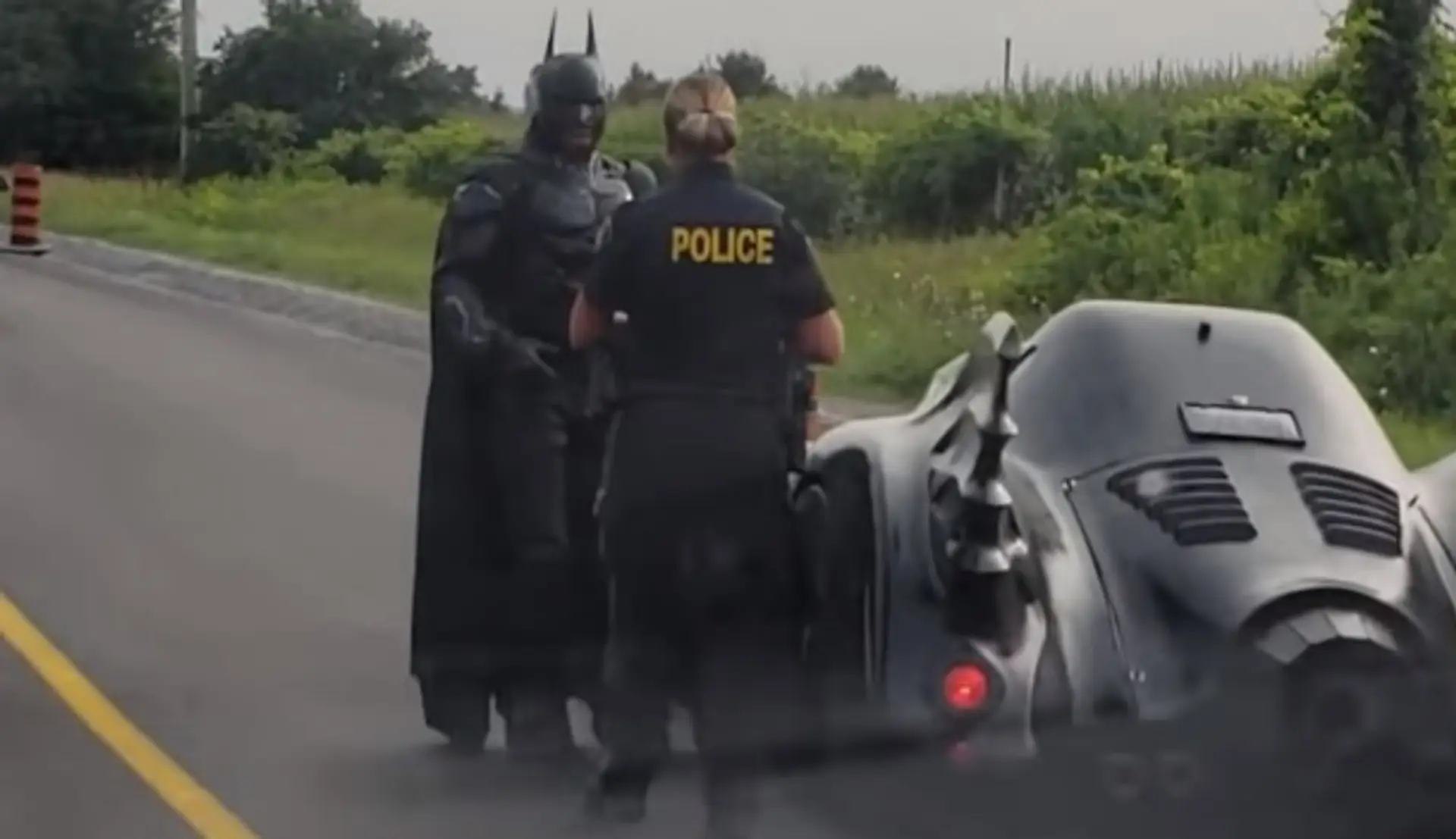 Policajtka kontroluje muža prezlečeného za Batmana.