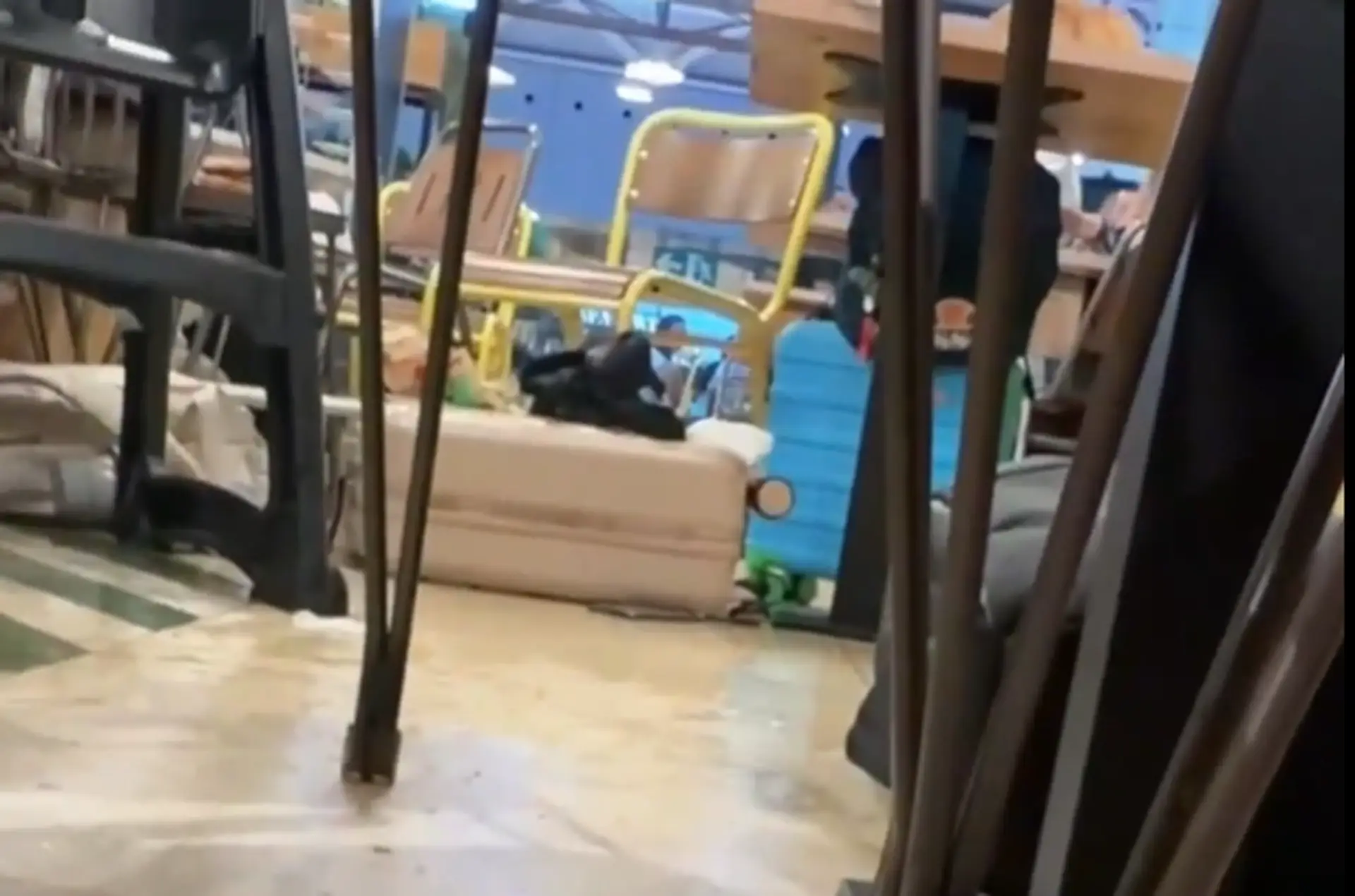 Žena leží pod stolom na letisku.