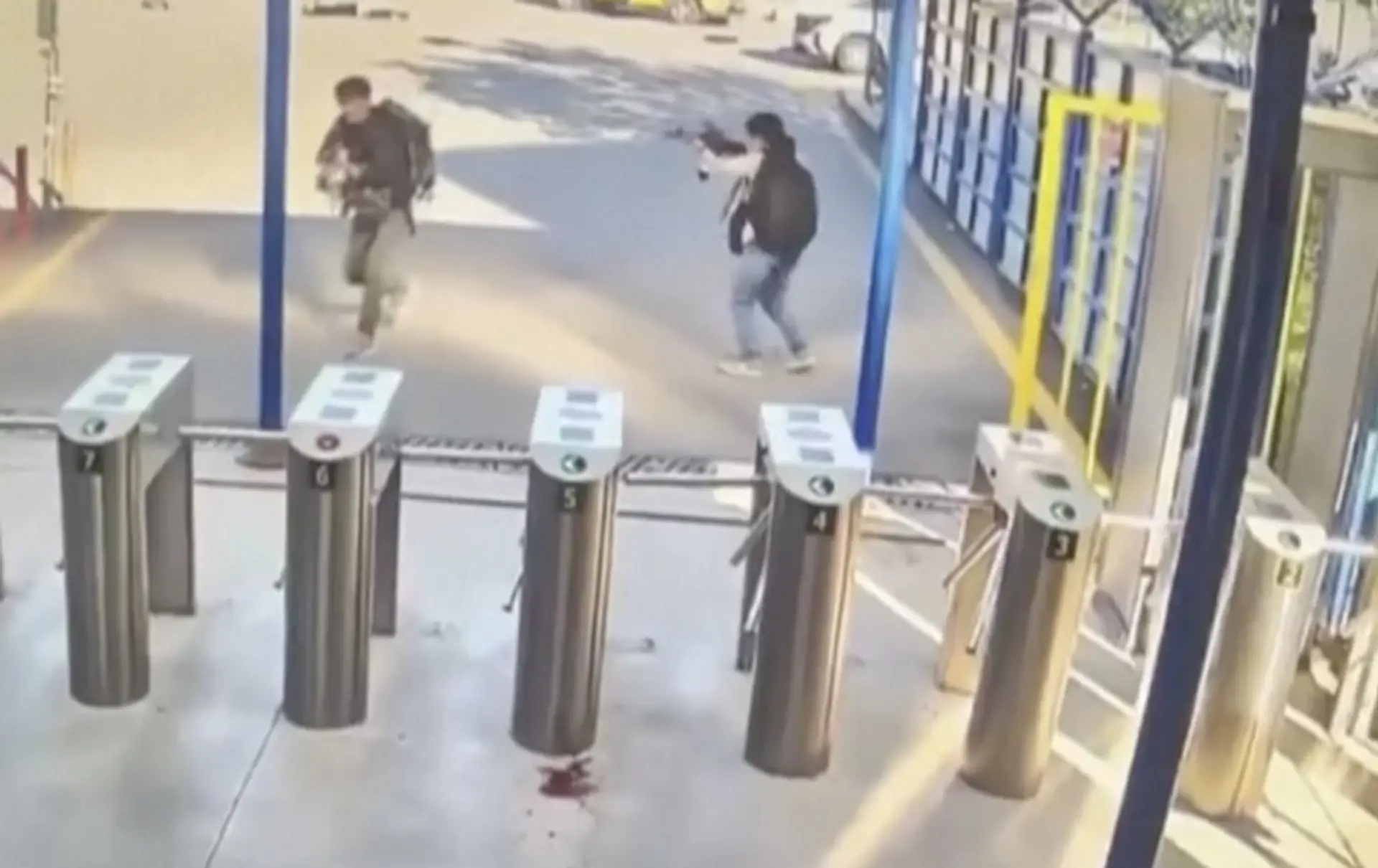 Na snímke z videa bezpečnostnej kamery dvaja ľudia so zbraňami a ruksakmi na chrbtoch počas teroristického útoku.