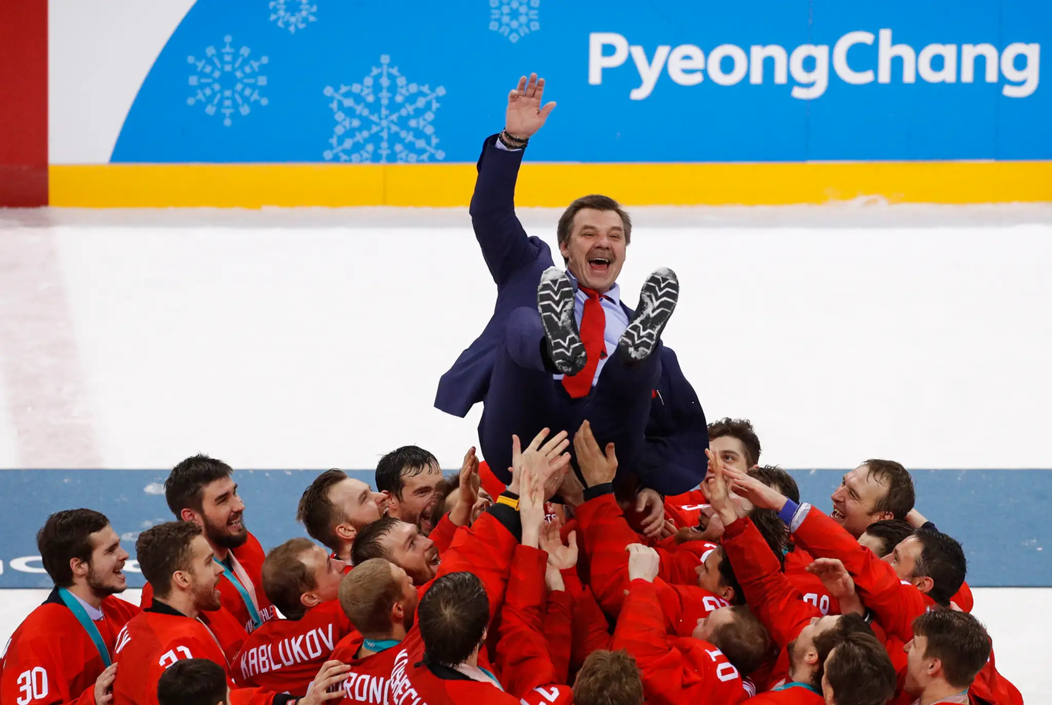 Olympijskí športovci z Ruska vyhadzujú nad hlavy svojho trénera Olega Znaroka po zisku zlatých olympijských medailí.